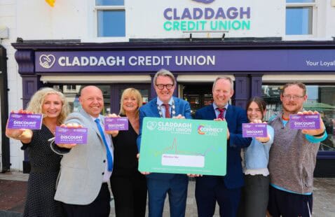 Women and Men smiling holding the Claddagh Credit Union Connect Card. 
