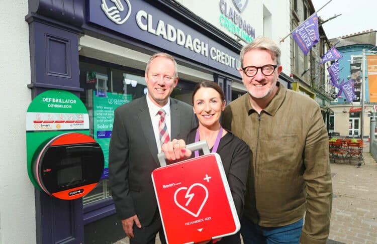 Image of two men and woman holding a defibrillator